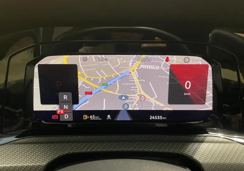 Vue rapprochée du tableau de bord numérique de la Volkswagen Golf 2024 affichant la navigation et la vitesse à 0 km/h.