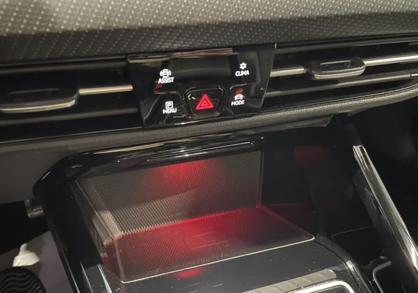 Gros plan sur la console centrale noire avec zone de charge à induction éclairée en rouge dans une Volkswagen Golf VIII R-Line blanche.