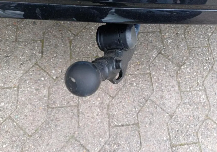 Gros plan sur l'attelage escamotable noir sous le pare-chocs arrière d'une Volkswagen Golf blanche.
