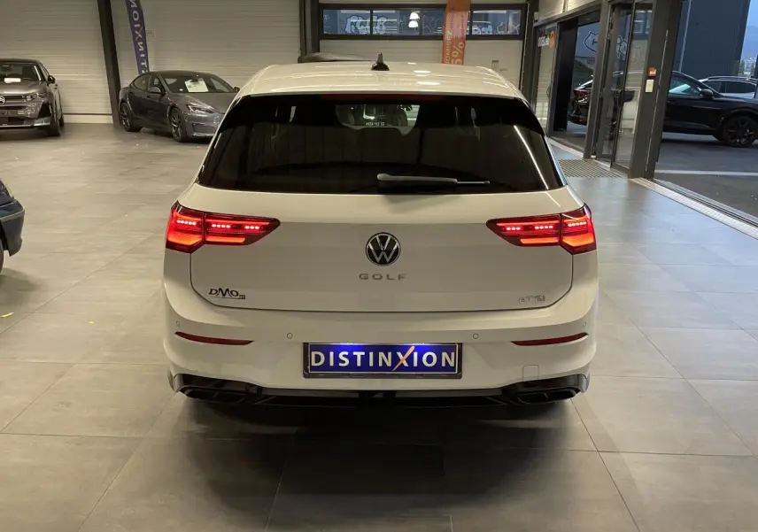 Vue arrière d'une Volkswagen Golf blanche 2024 avec feux LED allumés dans un showroom.