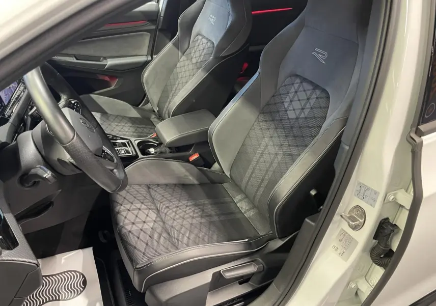 Vue intérieure côté conducteur de la Volkswagen Golf VIII R-Line blanche, sièges sport noirs avec surpiqûres et logo "R".