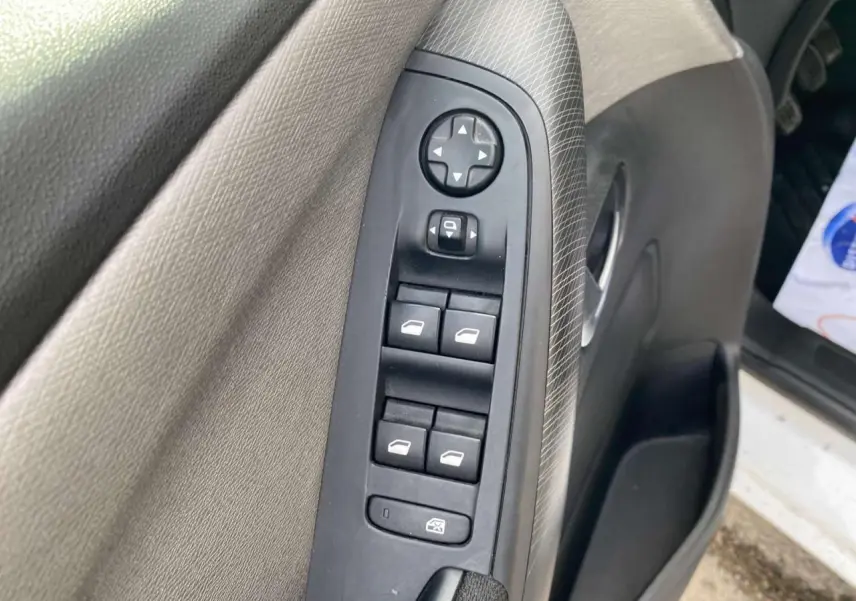 Panneau de commandes des vitres sur la porte avant gauche d'un Citroën Grand C4 Picasso blanc de 2015.
