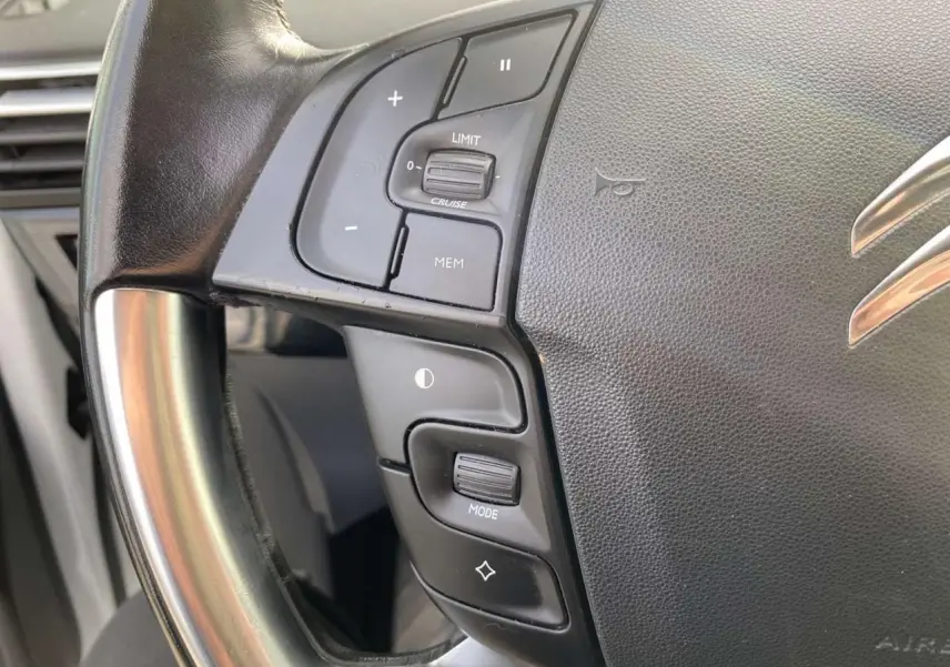 Gros plan sur le volant cuir noir du Citroën Grand C4 Picasso 2015, avec commandes intégrées côté gauche.