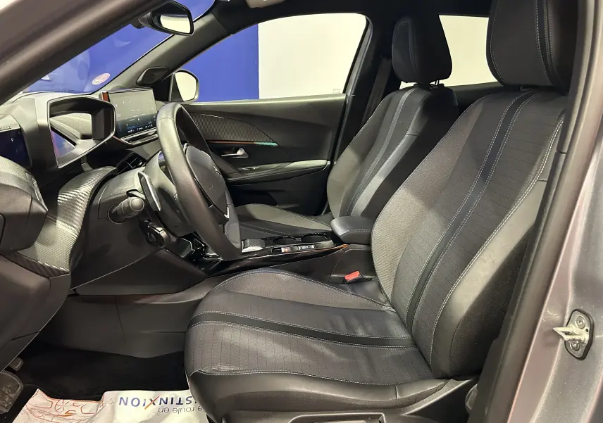 Vue intérieure côté gauche du poste de conduite d’un Peugeot 2008 gris Artense, avec sièges tissu et tableau de bord moderne.