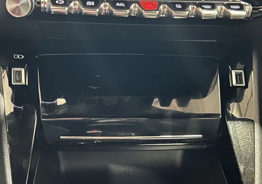 Vue rapprochée de la console centrale noire brillante du Peugeot 2008 avec boutons de commande et ports USB visibles.