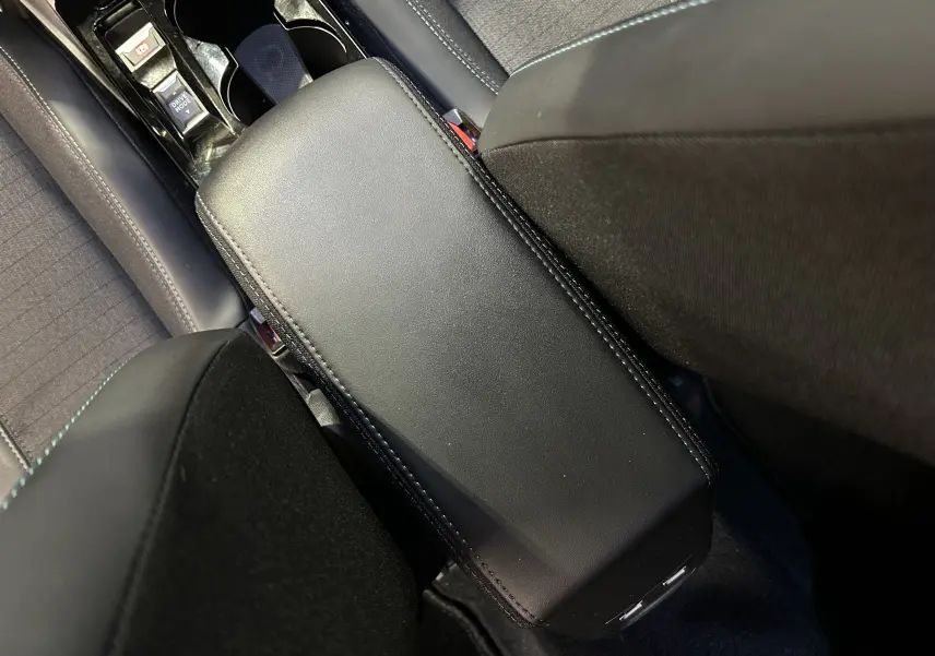 Vue rapprochée de l'accoudoir central noir entre les sièges avant du Peugeot 2008 gris Artense, intérieur tissu et cuir.