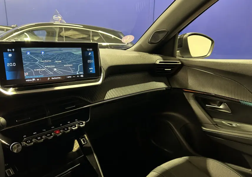 Vue intérieure côté passager du Peugeot 2008 gris Artense 2023, avec écran tactile GPS et détails carbone sur la planche de bord.