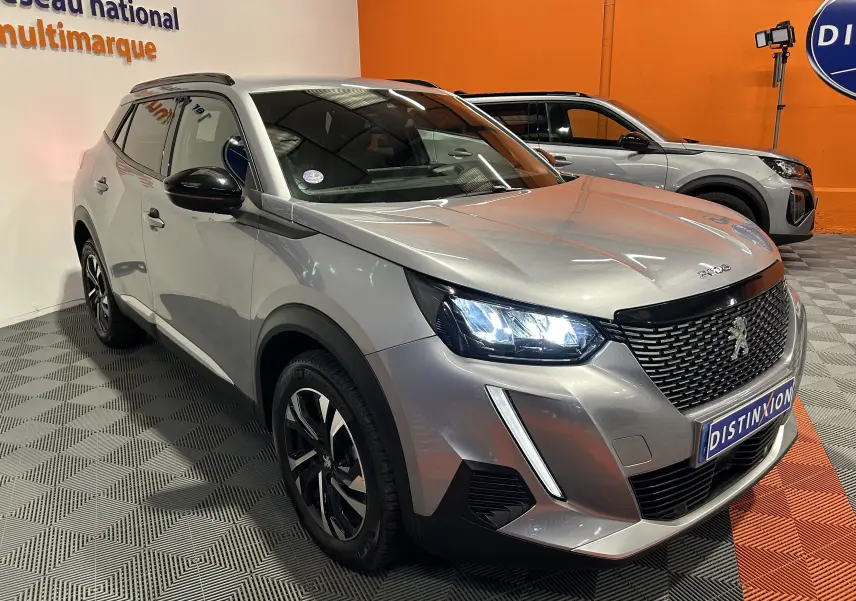 Peugeot 2008 gris Artense en 3/4 avant droit, phares LED allumés et calandre noire distinctive.