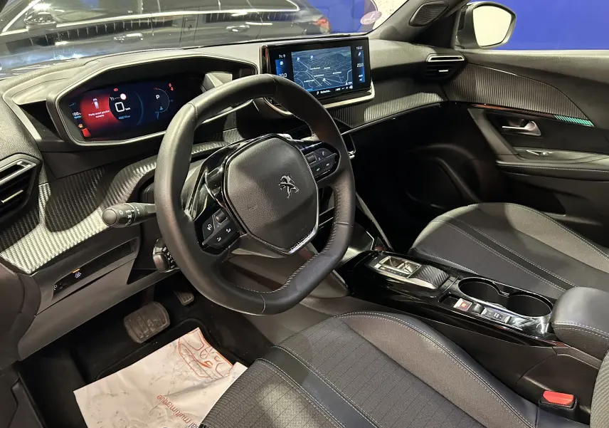 Vue intérieure côté conducteur du Peugeot 2008 gris Artense 2023, avec tableau de bord numérique et écran central tactile GPS allumé.