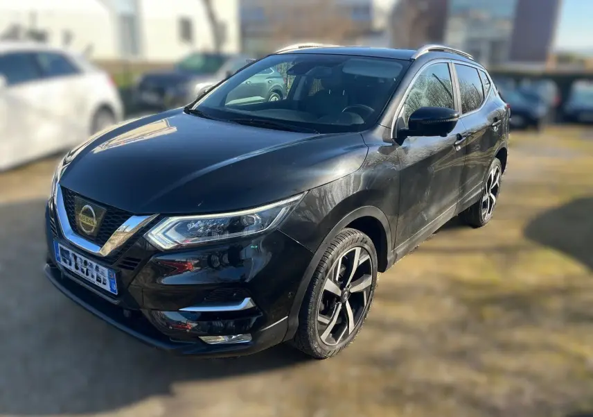 Vue 3/4 avant droit d'un Nissan Qashqai noir avec jantes alliage et calandre chromée dans un garage en bois.