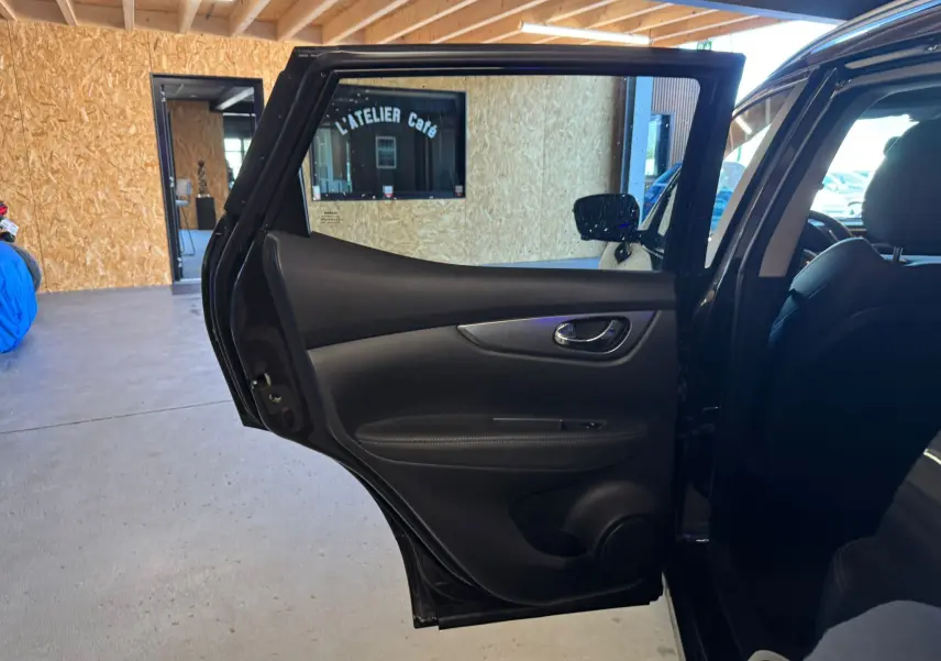 Vue intérieure de la porte arrière gauche noire ouverte d'un Nissan Qashqai II PH2 2017, avec garniture en cuir noir.