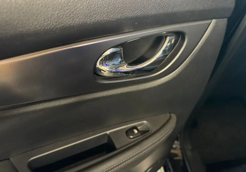 Poignée de porte intérieure chromée côté conducteur du Nissan Qashqai noir, avec bouton de verrouillage des portes.