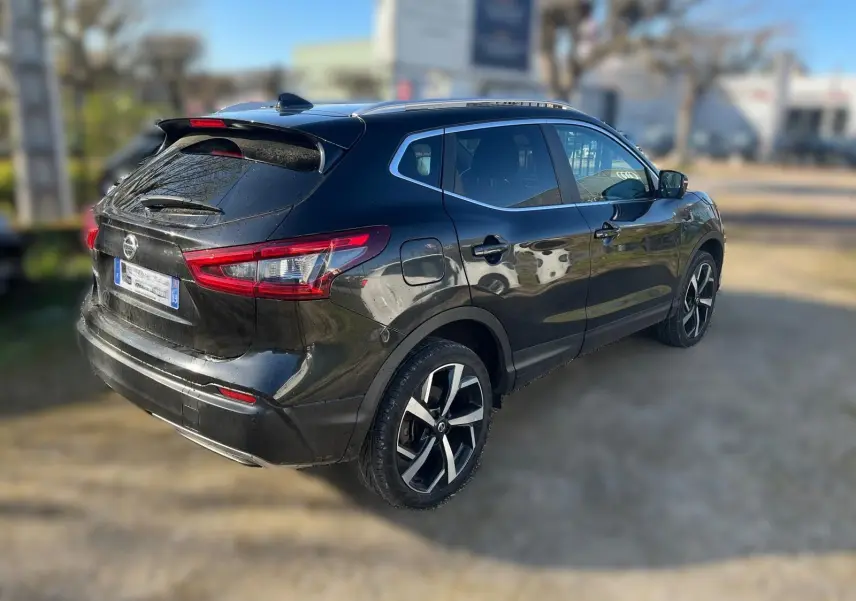 Vue avant d'un Nissan Qashqai II PH2 noir avec calandre chromée et plaque Distinxion en intérieur d'atelier.