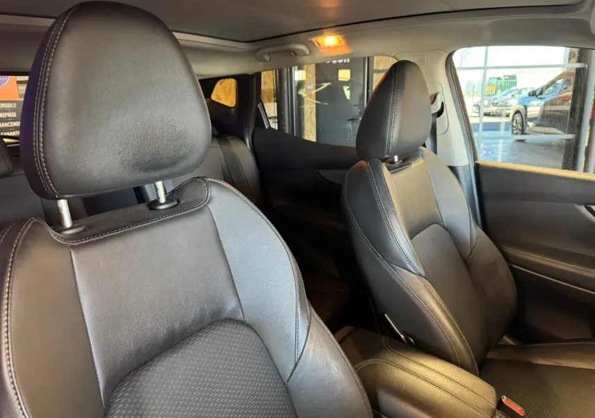 Vue intérieure rapprochée des sièges avant en cuir noir du Nissan Qashqai II PH2 2017 avec accoudoir central.