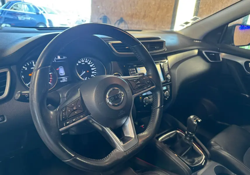 Vue intérieure côté conducteur du Nissan Qashqai noir 2017, volant cuir multifonctions et levier de vitesse manuel visibles.