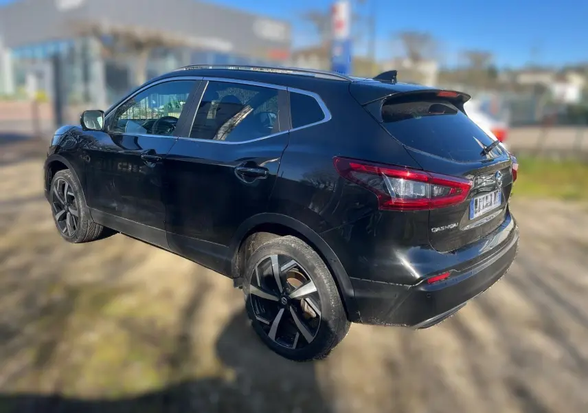Nissan Qashqai noir vu de face en léger 3/4 avant droit, avec calandre chromée et jantes alu visibles.