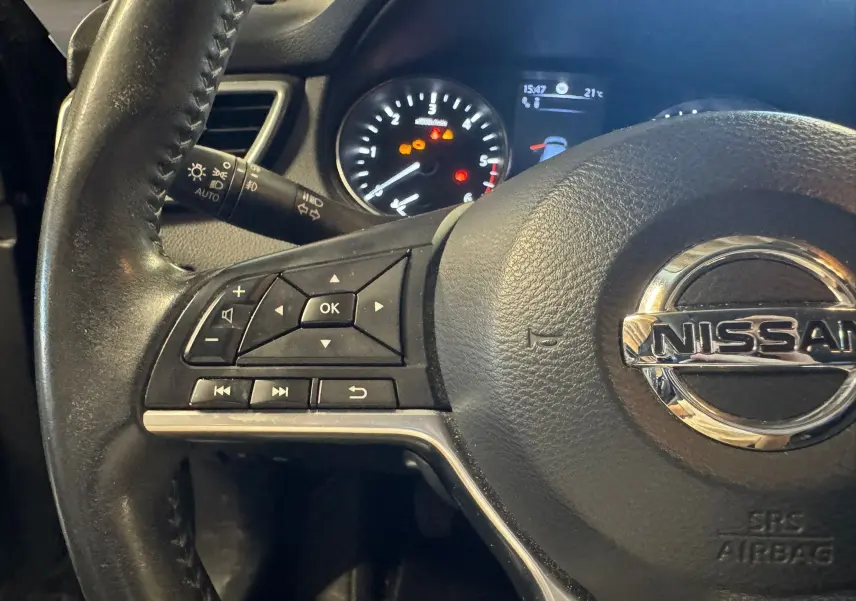 Gros plan sur le volant cuir noir multifonctions du Nissan Qashqai avec commandes intégrées et tableau de bord en arrière-plan.