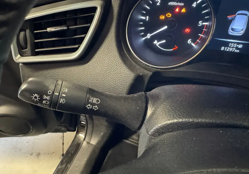 Gros plan sur la commande des phares et clignotants côté gauche du tableau de bord noir du Nissan Qashqai 2017.