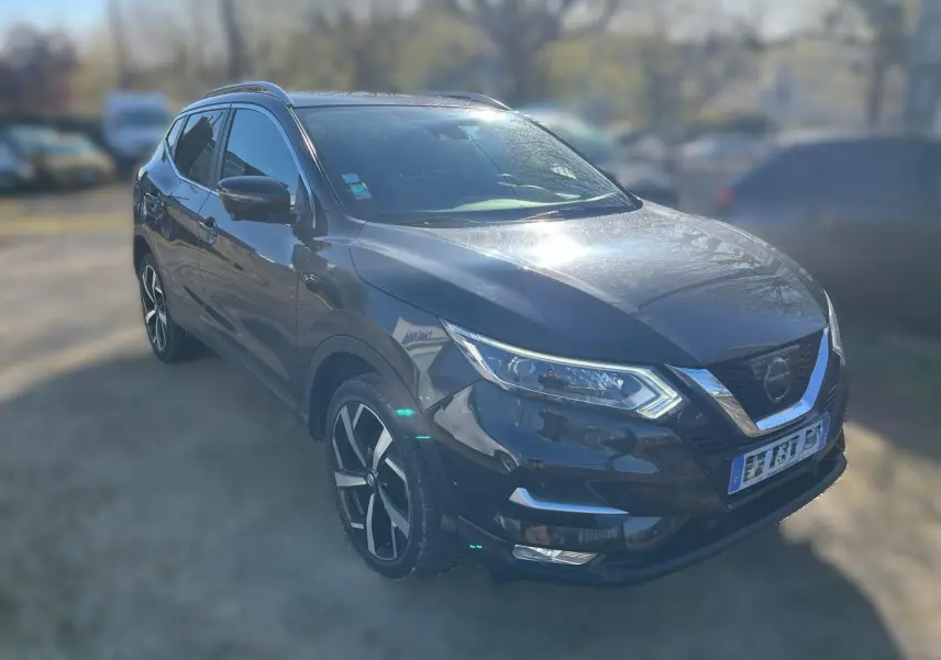 Vue de profil côté gauche d'un Nissan Qashqai noir 2017 avec jantes alliage et barres de toit en intérieur d'atelier.
