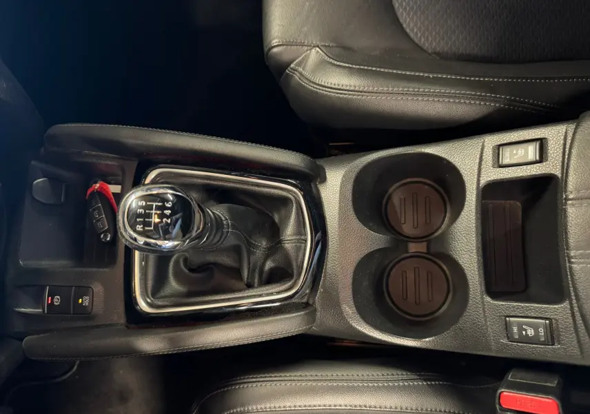 Vue plongeante sur la console centrale noire du Nissan Qashqai 2017 avec levier de vitesse manuel et commandes sièges chauffants.