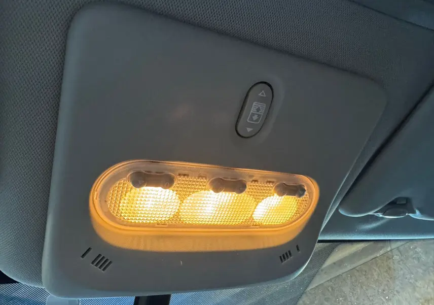 Plafonnier intérieur allumé avec commandes d'ouverture du toit panoramique du Nissan Qashqai noir, vue de dessous.