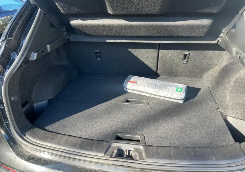 Vue 3/4 arrière droite d'un Nissan Qashqai noir 2017 avec jantes alu et barres de toit, stationné en intérieur.