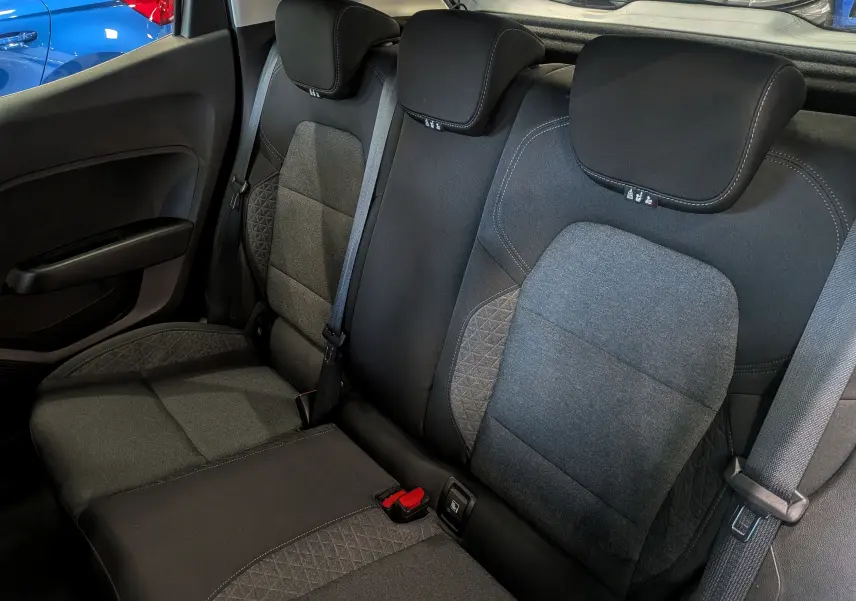 Vue intérieure des sièges arrière en tissu gris et noir de la Renault Clio V Business, avec ceintures de sécurité visibles.
