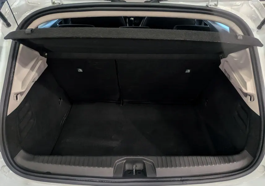 Coffre ouvert vu de l'arrière d'une Renault Clio V Blanc Glacier, montrant l'espace de chargement vide et la tablette arrière relevée.