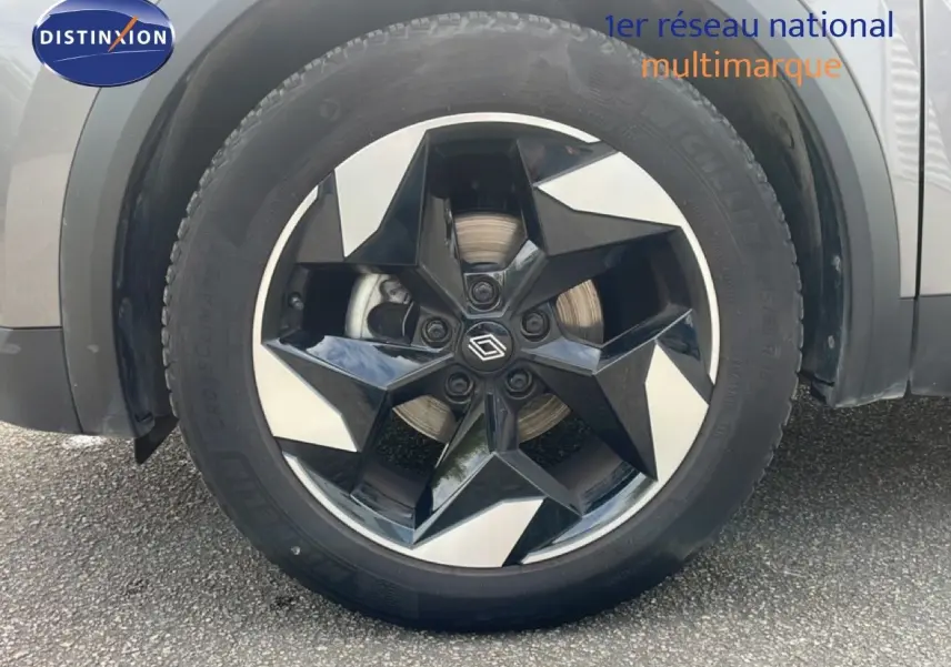 Gros plan sur la roue avant droite du Renault Captur gris Cassiopée métal avec jante alliage noire et argentée au design étoilé.