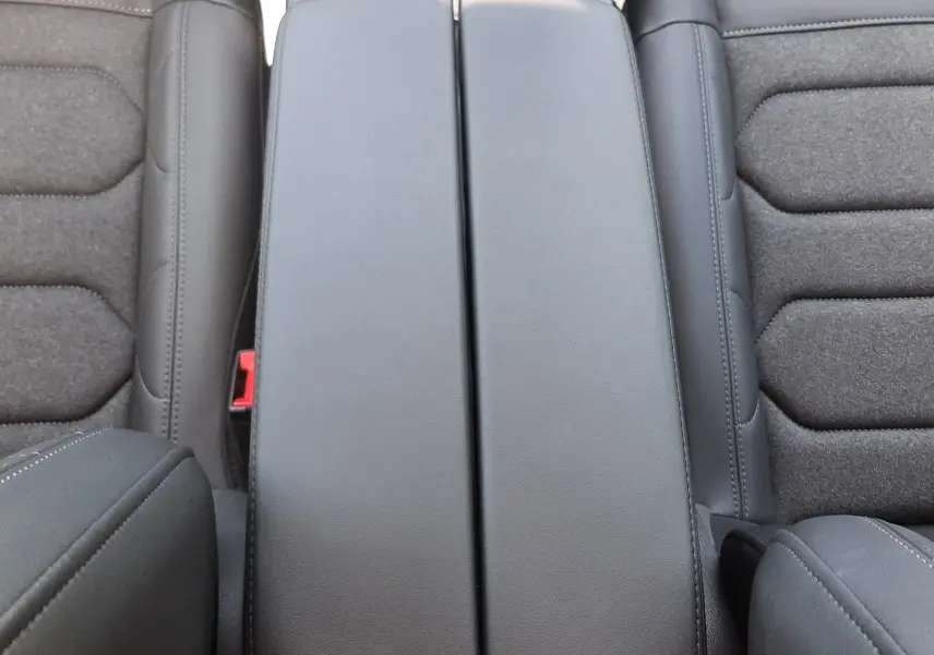 Vue plongeante sur l'accoudoir central noir et les sièges gris foncé du Citroën C5 Aircross Ph.2 Hybrid 2025.