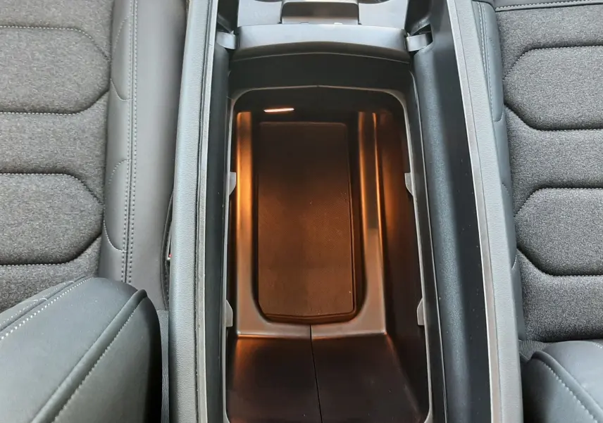 Vue plongeante sur la console centrale ouverte du Citroën C5 Aircross noir Perla Nera, montrant un rangement intérieur éclairé.