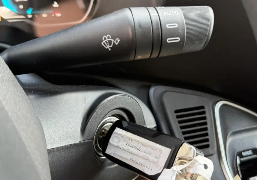 Gros plan sur le contacteur de clé et le commodo d’essuie-glace dans l’habitacle noir de l’Iveco Daily blanc.