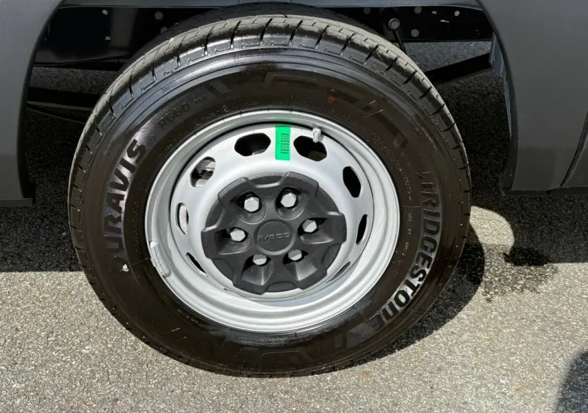 Gros plan sur la roue avant droite du fourgon Iveco Daily blanc, jante acier grise avec pneu Bridgestone.