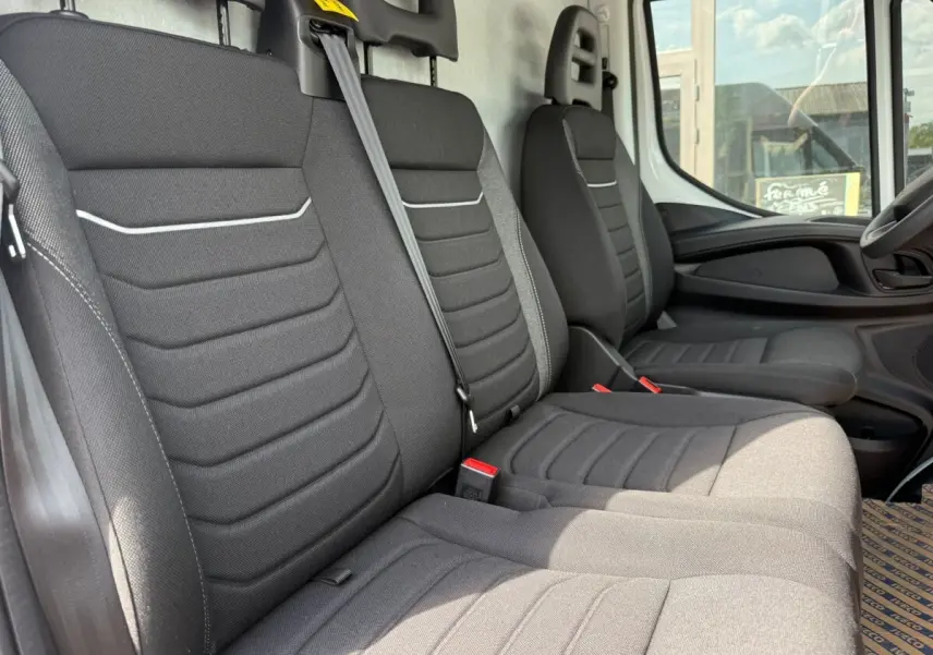 Vue intérieure côté droit montrant les sièges avant gris foncé du fourgon Iveco Daily 2.3 35S16 V12 blanc de 2026.