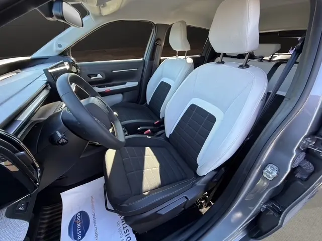 Vue intérieure côté conducteur de la Citroën C3 Turbo 100 BVM6 MAX 2025 gris foncé, sièges bicolores noir et clair, volant cuir multifonctions.
