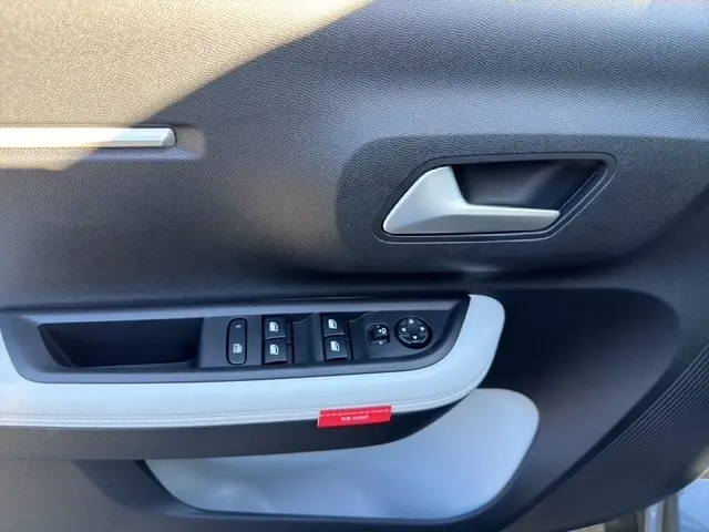 Gros plan sur la porte intérieure côté conducteur de la Citroën C3 gris foncé, avec commandes électriques et poignée argentée.