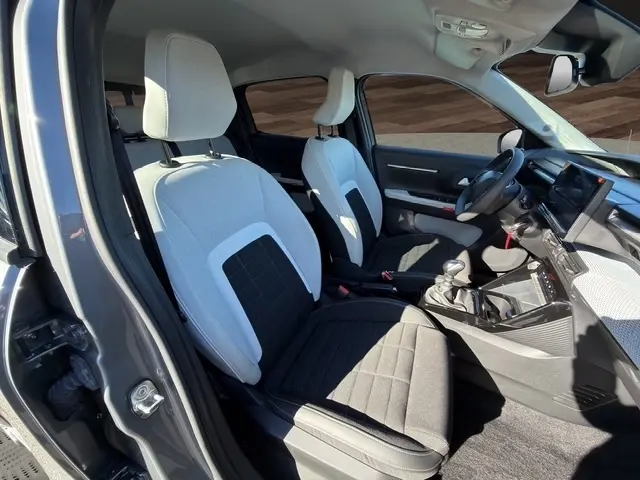 Intérieur avant de la Citroën C3 gris foncé 2025, sièges bicolores, volant cuir et écran tactile central visible.