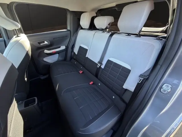 Vue intérieure arrière côté droit de la Citroën C3 gris foncé, montrant la banquette bicolore noire et grise avec appuie-têtes.
