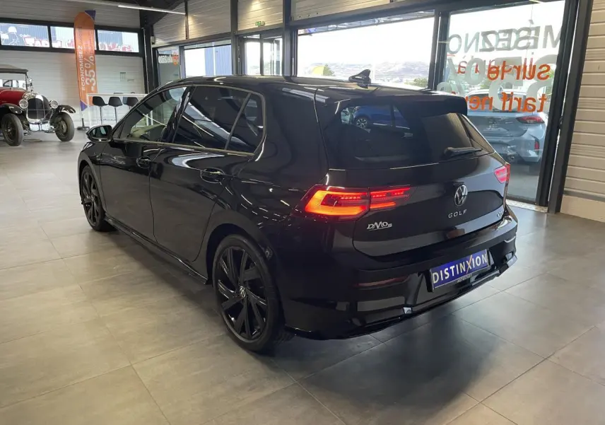Volkswagen Golf VIII R-Line Black noir métal vue 3/4 arrière droit avec jantes noires 18 pouces en intérieur showroom.