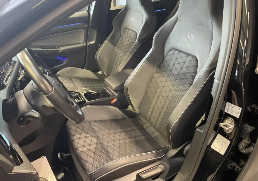 Vue intérieure côté conducteur de la Volkswagen Golf VIII R-Line Black 2024 avec sièges sport gris à motif losanges.