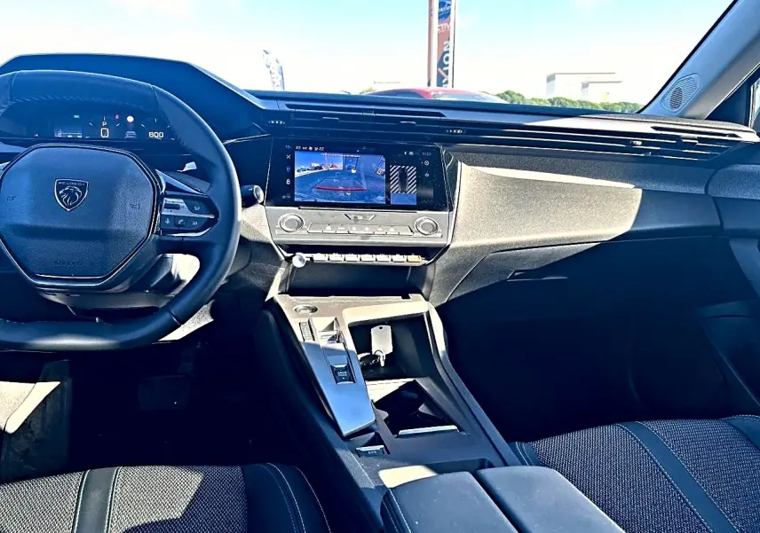Vue intérieure avant de la Peugeot 308 2025, tableau de bord moderne avec écran tactile et volant multifonction noir.