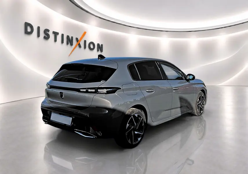 Vue 3/4 arrière droite d'une Peugeot 308 gris selenium avec jantes alu noires et vitres arrière surteintées dans un studio lumineux.