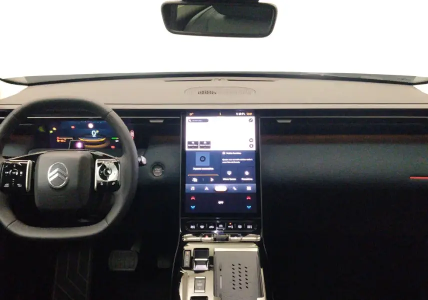 Vue intérieure frontale du tableau de bord noir de la Citroën C5 hybride avec écran tactile vertical et volant multifonctions.