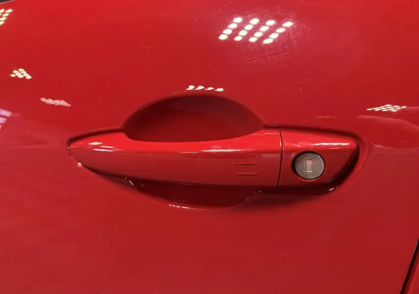 Poignée de porte rouge foncé de la FIAT 600 Hybrid 2025, avec serrure intégrée côté droit.