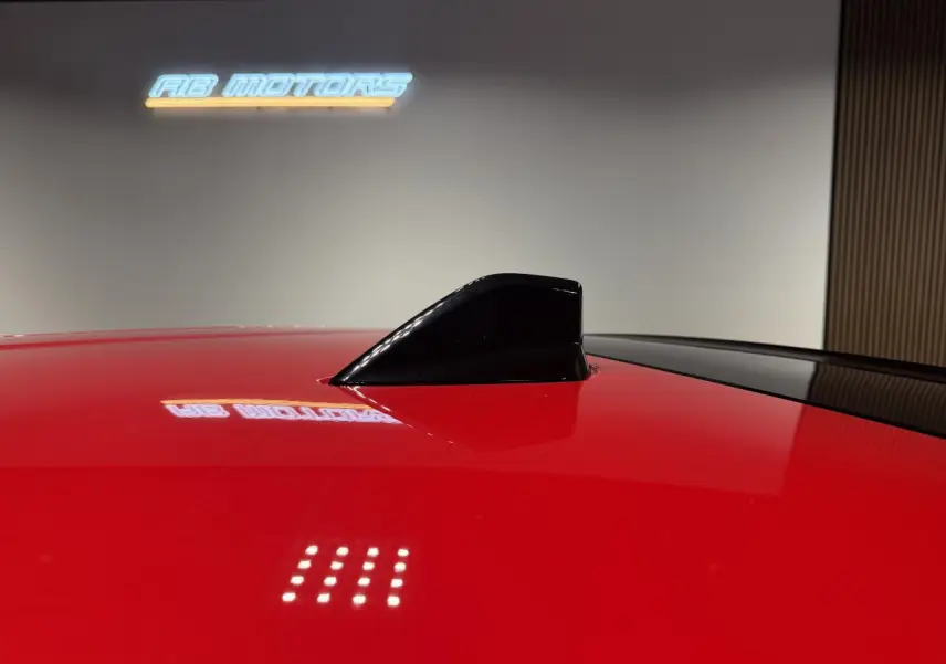 Gros plan sur l'antenne requin noire brillante sur le toit rouge foncé de la FIAT 600 Hybrid 2025.