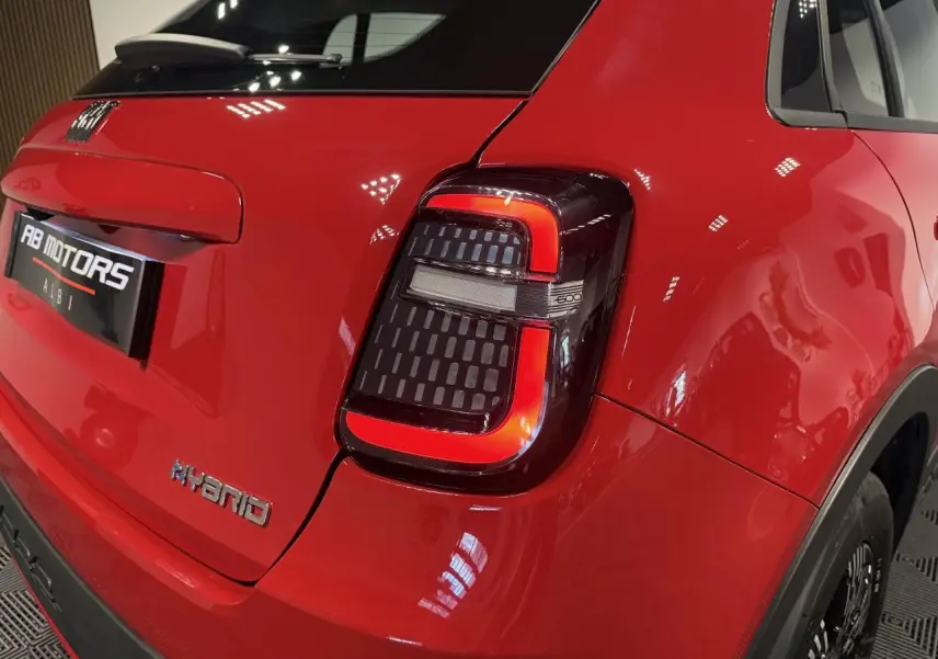 Vue 3/4 arrière droite d'une FIAT 600 rouge foncé avec feux arrière LED en forme de U et logo Hybrid sur le hayon.