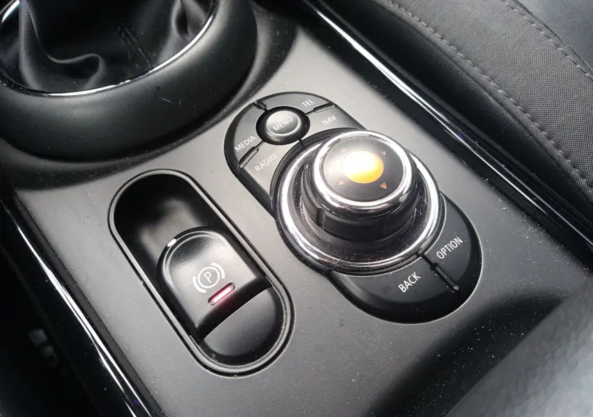 Gros plan sur la molette de commande centrale noire et le frein à main électrique dans l'habitacle d'une MINI Clubman 2017.