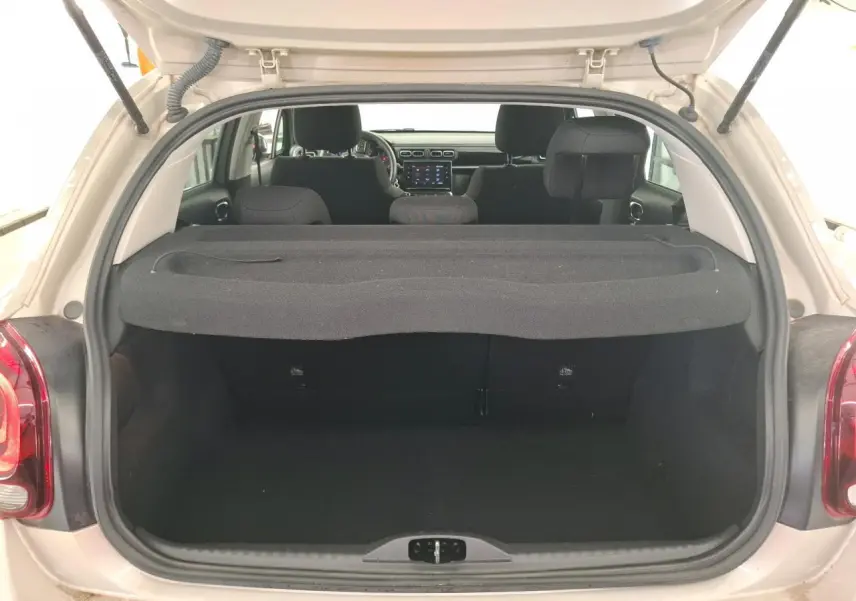 Coffre ouvert d'une Citroën C3 beige clair vue arrière, montrant l'intérieur noir et tablette cache-bagages.