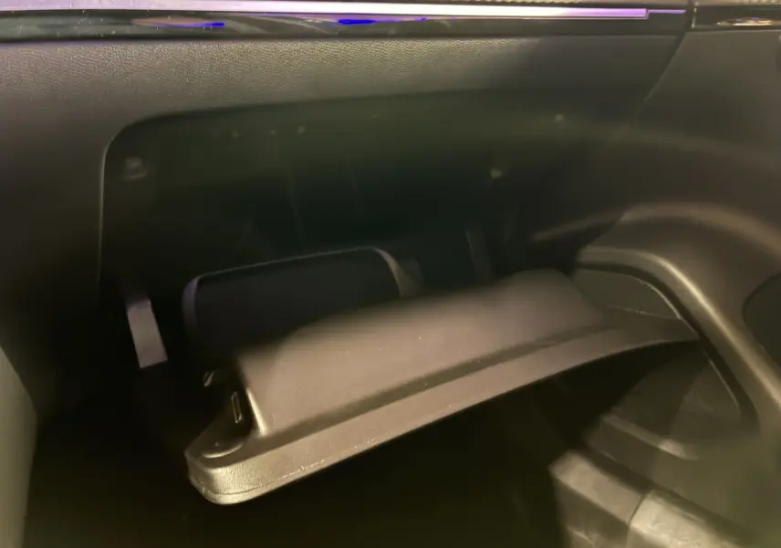 Gros plan sur la boîte à gants ouverte de la Peugeot 2008 1.2 Hybrid 136 Allure, intérieur noir, détail du rangement côté passager.