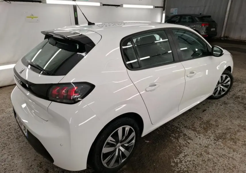 Peugeot 208 blanche vue 3/4 arrière droit, avec feux arrière noirs et jantes alliage bicolores.